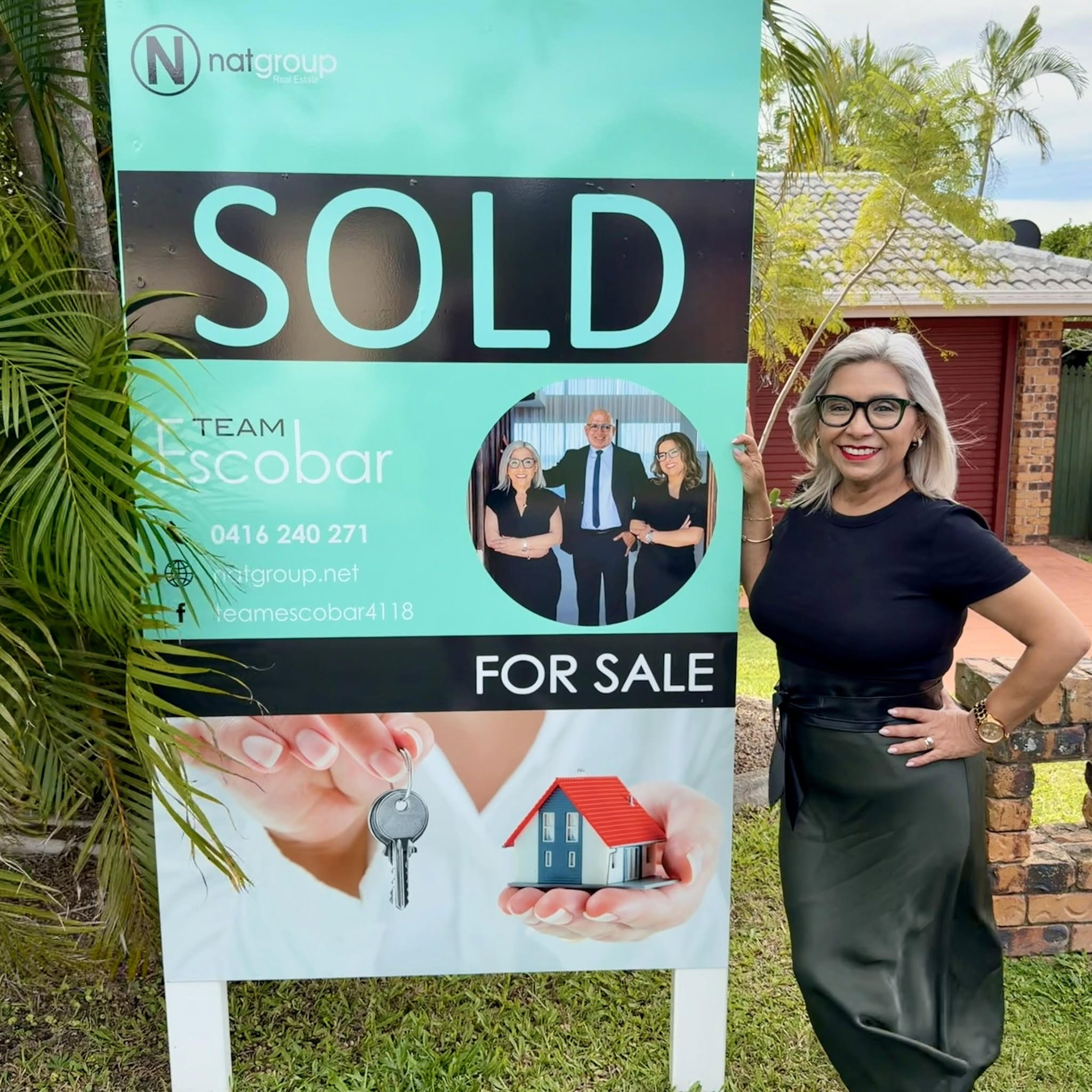 Claudia beside a Natgroup SOLD sign